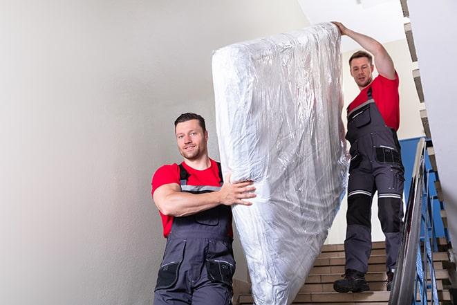 team of workers lifting a box spring out of a house in Brooklyn