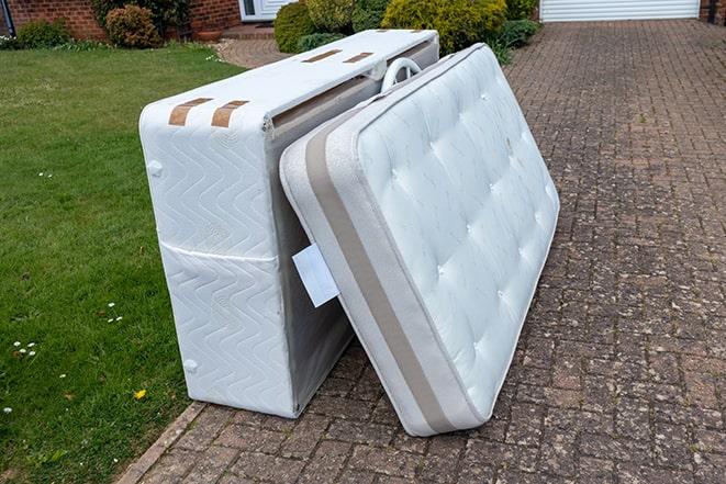 team loading mattresses into a large dumpster